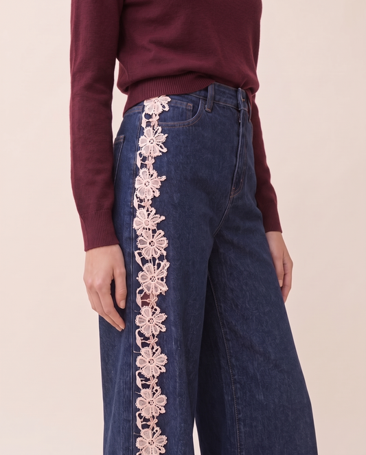 Waist-down view of dark blue high-waisted jeans with cream lace side panel