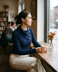 Women's Asymmetric Cowl Neck Top in navy blue, worn in a cozy café by the window with a latte