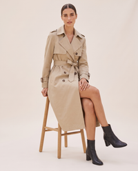 Classic Double-Breasted Belted Trench Coat — worn seated