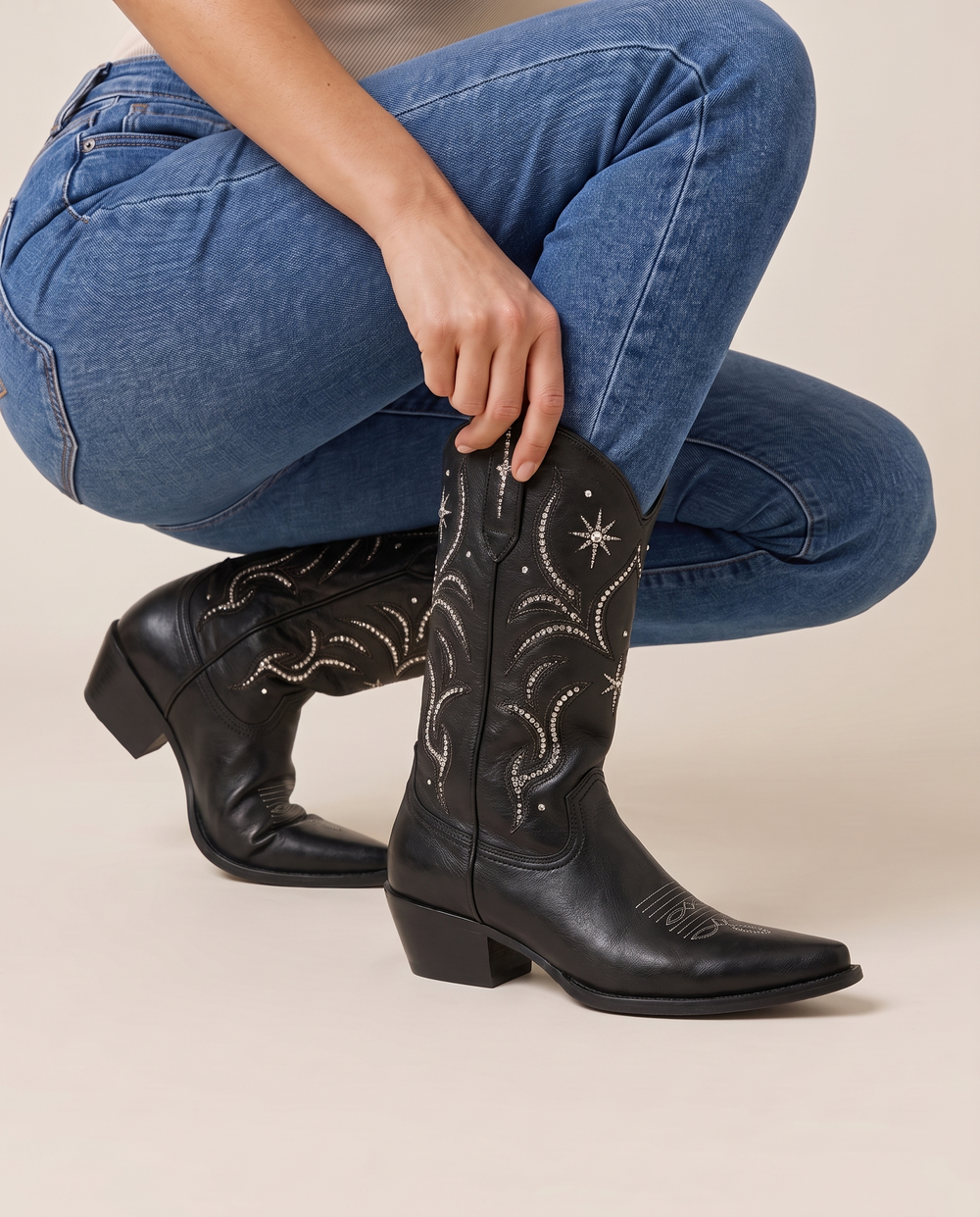 Black Embellished Mid-Calf Cowboy Boots — pulling on the boot with jeans