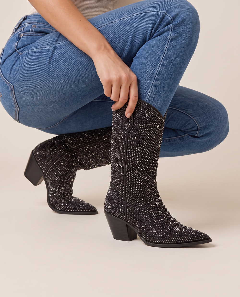Rhinestone Cowboy Boots Mid-Calf in Black — pulling on the boot with jeans