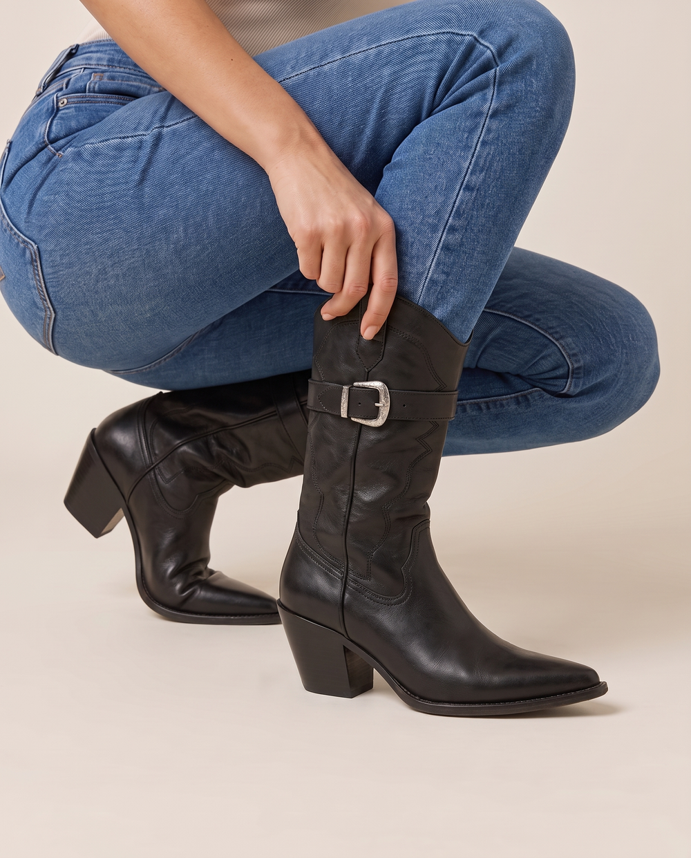 Leather Cowboy Boots with Buckle Detail — pulling on the boot with jeans
