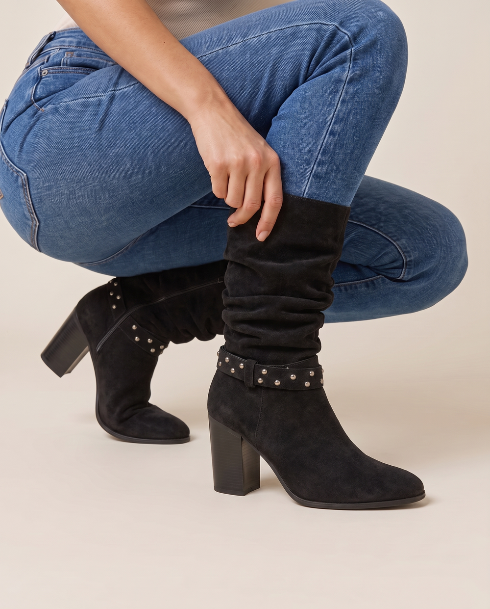 Slouchy Suede Mid-Calf Boots with Stud Strap — pulling on the boot with jeans