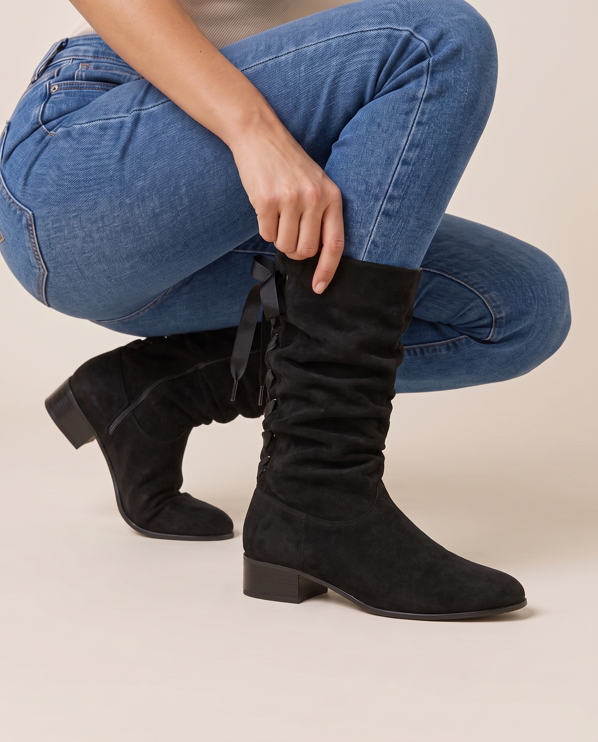 Slouchy Mid-Calf Boots with Ribbon Lace-Up Back — pulling on the boot with jeans
