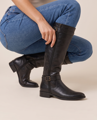 Knee-High Riding Boots with Buckle Straps and Low Block Heel — pulling on the boot with jeans