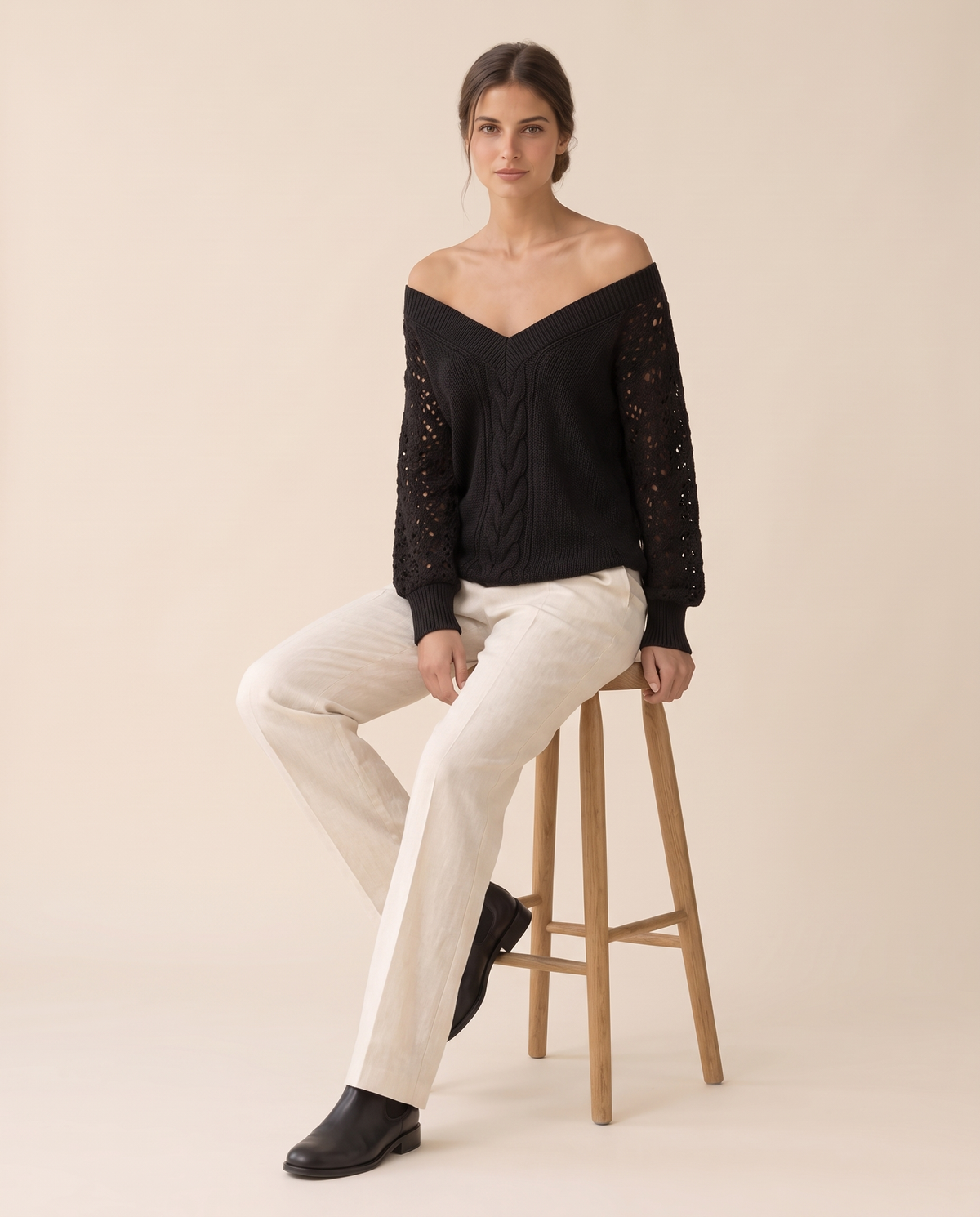 Ischia Relaxed Off-Shoulder Cable Knit V-Neck Sweater — worn seated