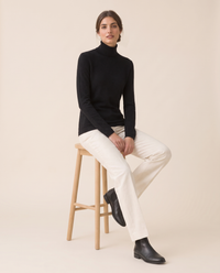 Merano Classic Solid Knit Turtleneck Sweater — worn seated