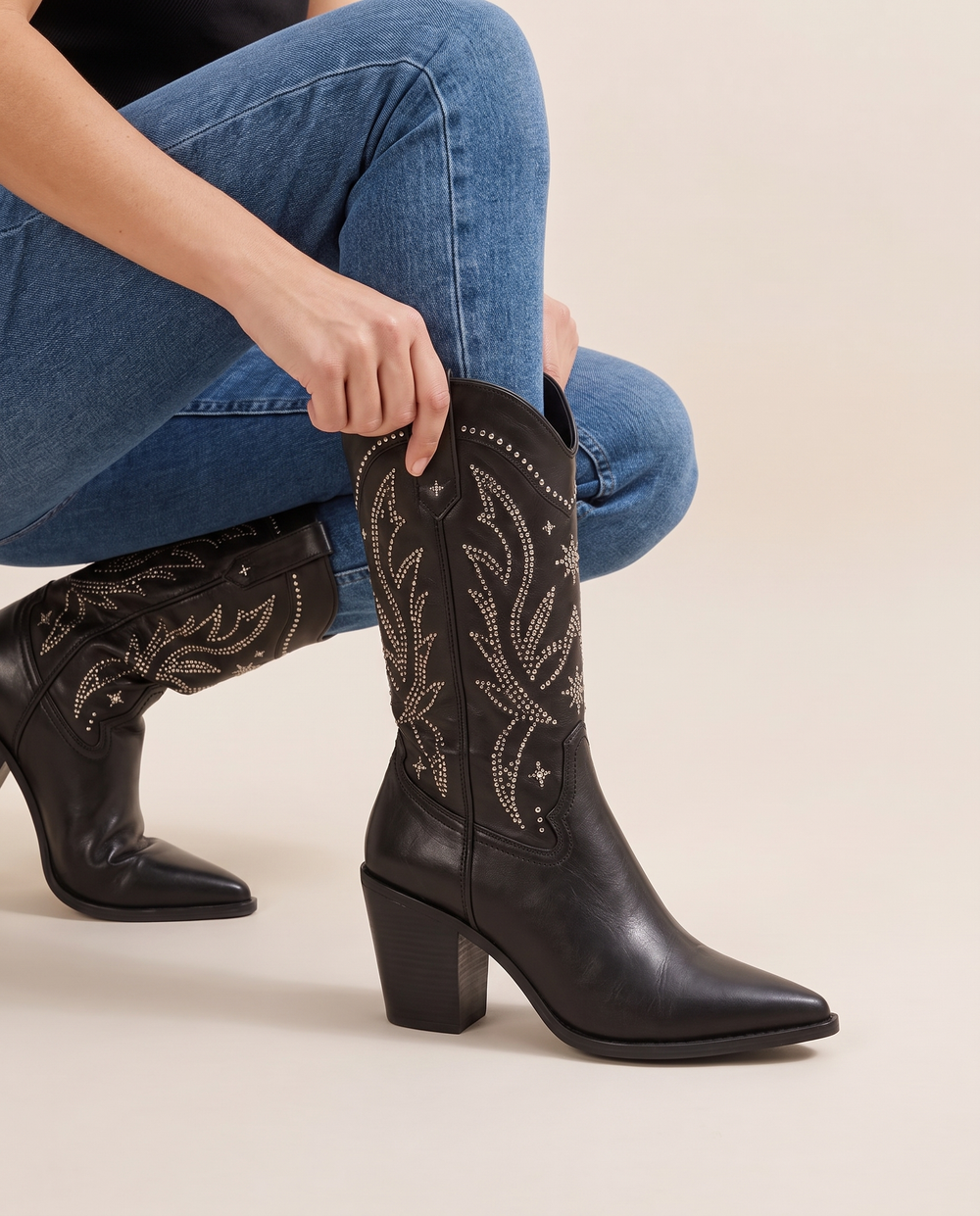 Black Embellished Mid-Calf Cowboy Boots — pulling on the boot with jeans