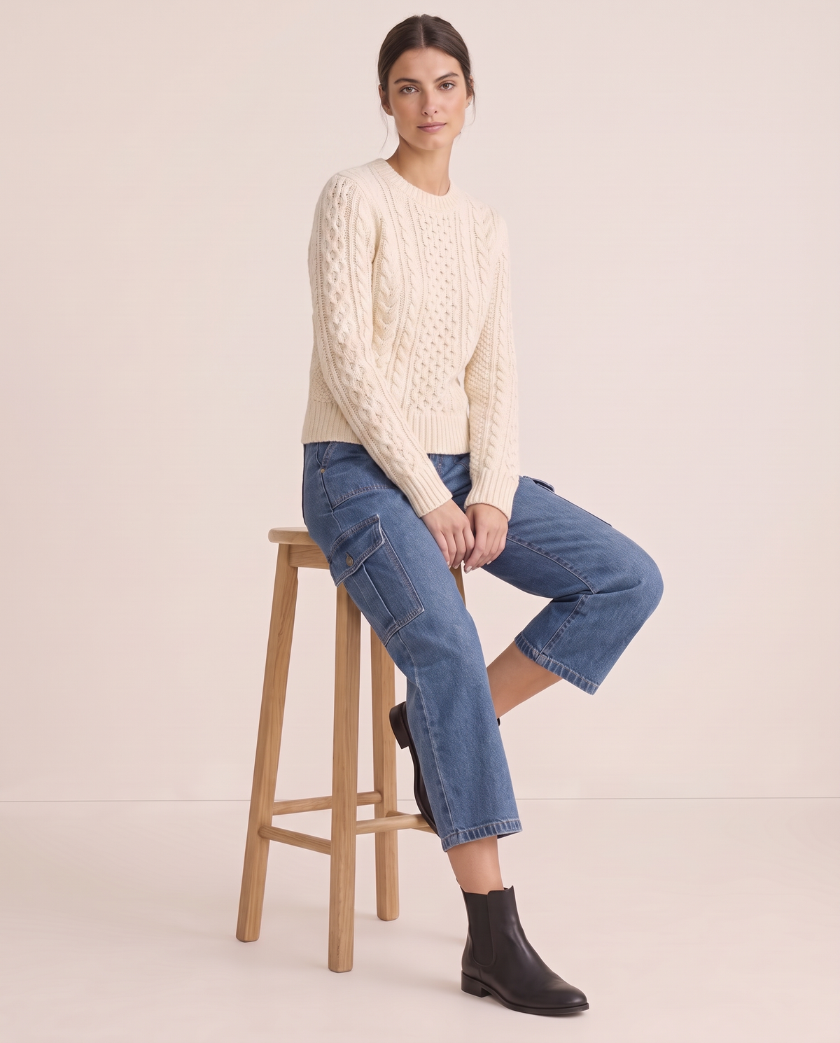 Blue cropped cargo jeans, seated on a stool