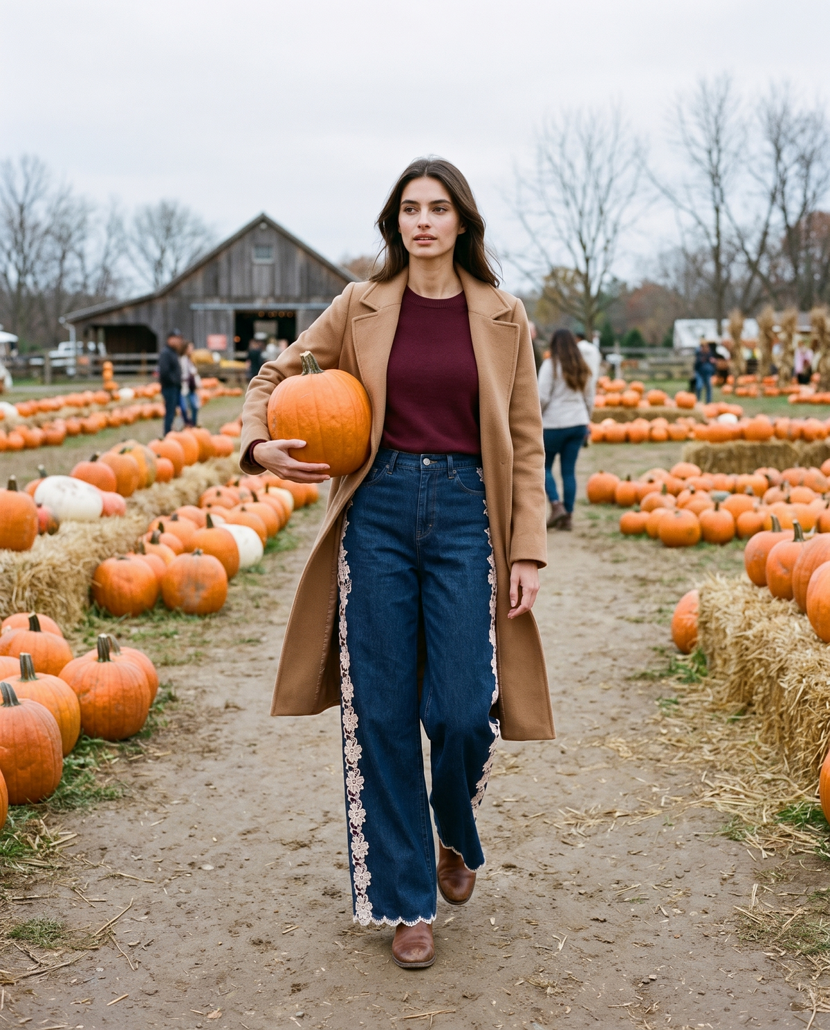 Lace-inset jeans worn with a camel coat while carrying a pumpkin