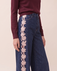 Waist-down view of dark blue high-waisted jeans with cream lace side panel
