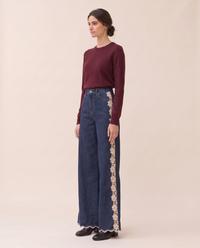Three-quarter view of lace-inset wide-leg jeans with a burgundy knit sweater