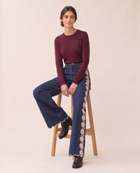 Model seated on a stool in lace-inset wide-leg jeans