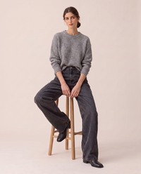 Kristin Baggy Jeans in black wash, seated on a stool