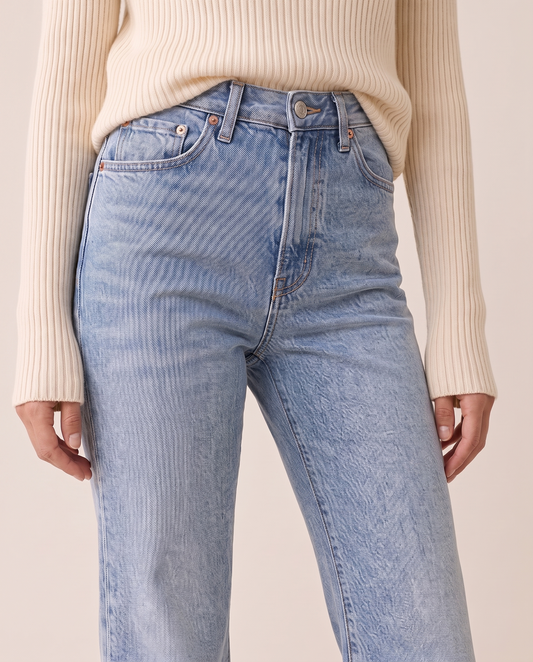 Close view of light blue high-rise flare jeans with a cream ribbed turtleneck