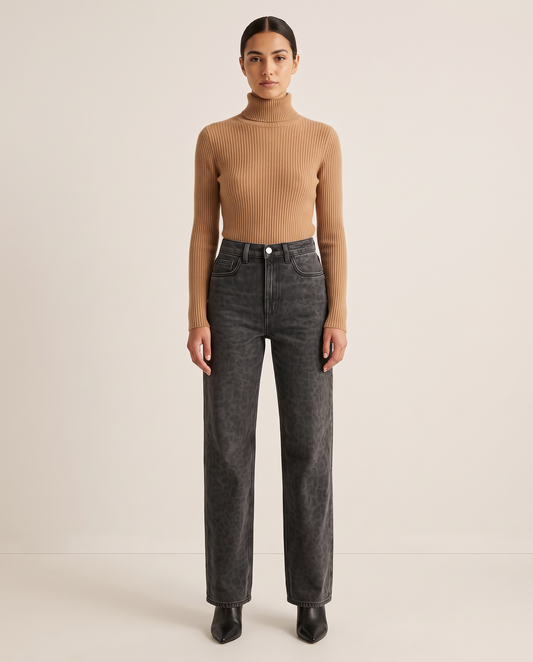 Woman wearing black leopard print straight-leg jeans with a camel turtleneck and black ankle boots, studio front view