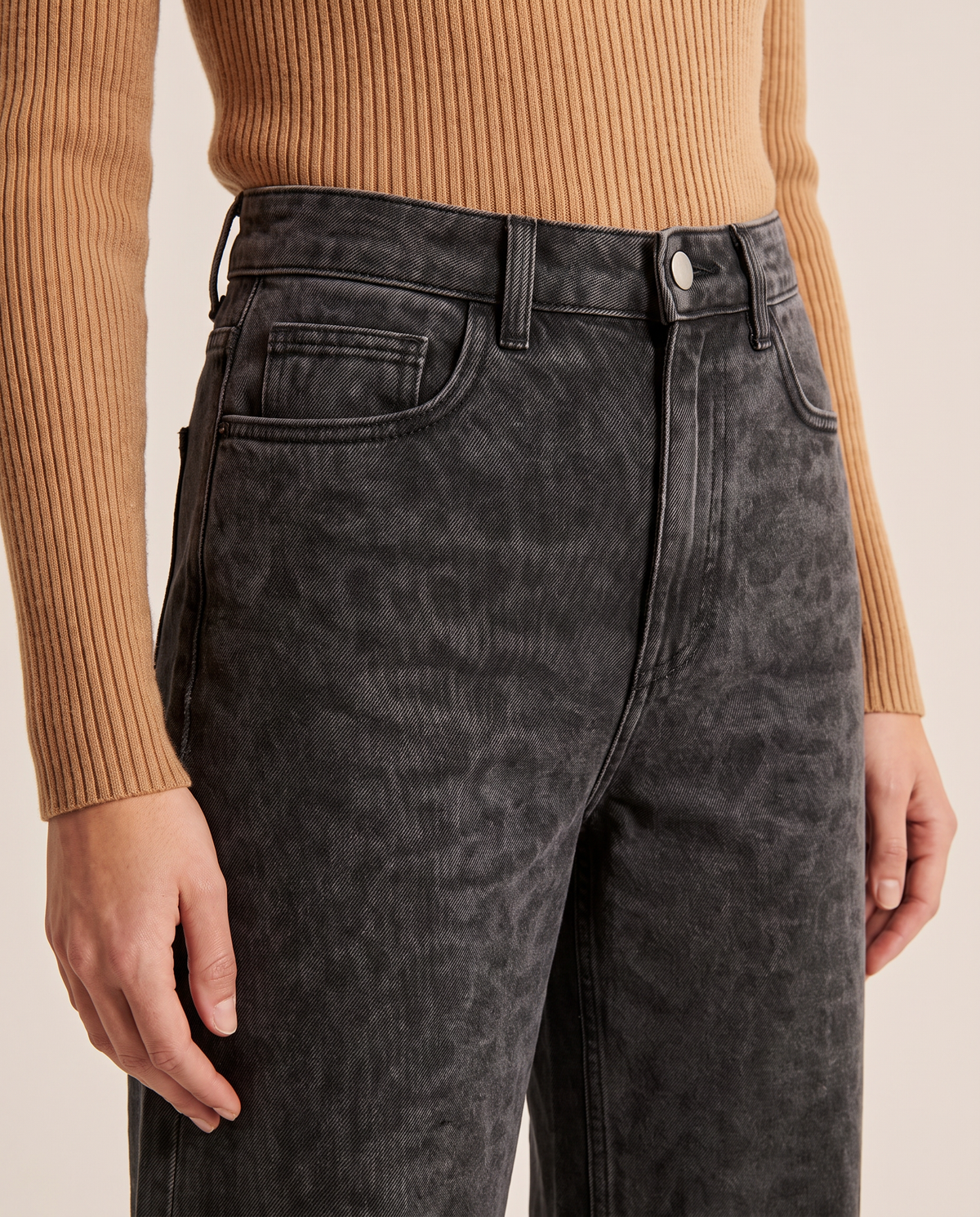 Close-up of the high waist, button and front pocket on black leopard print jeans
