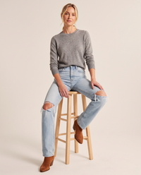 Light blue ripped straight jeans, seated on a wooden stool