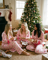 Women's Christmas Pajamas, Satin Bow-Cuff PJ Set — girlfriends in matching Pink Santa pajamas opening presents by the tree