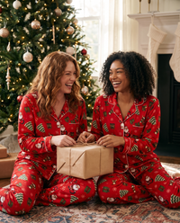 Women's Christmas Pajamas, Santa Claus Print Button-Up PJ Set — friends in matching red pajamas opening presents by the tree on Christmas morning