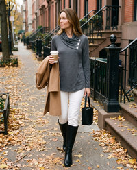 Women's Asymmetric Cowl Neck Top in charcoal gray, worn with white jeans and knee boots on a New York brownstone street in fall