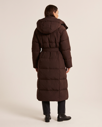 Women's Long Belted Puffer Coat in chocolate brown — studio back view with hood