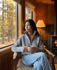Zip-up knit cardigan worn in a cozy cabin